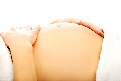 Pregnant woman massagin her growing belly